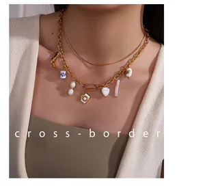 Detail of layered gold chain necklace with freshwater pearl and floral ceramic pendants