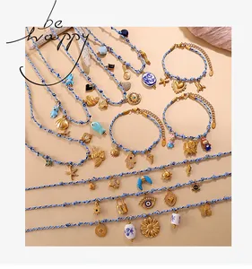 Detail of blue woven rope necklaces and bracelets with gold marine-themed charms and beads