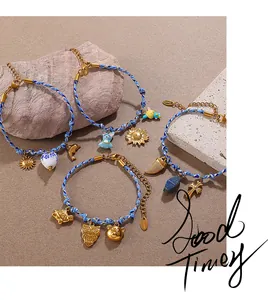 Detailed view of woven blue and white cord bracelets with various gold enamel charms