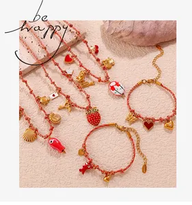 Detailed collection of red woven bracelets and necklaces with gold nautical pendants