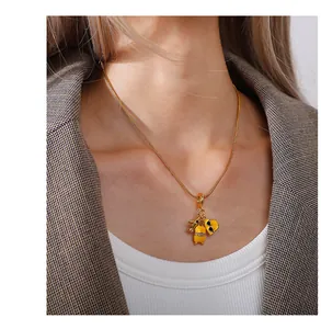 Dettaglio della collana dorata con ciondoli a tema viaggio, valigia e aereo in miniatura