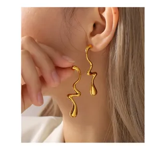 Gros plan de boucles d'oreilles dorées irrégulières en forme de goutte d'eau ondulée