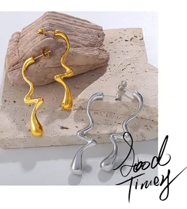 Détail de boucles d'oreilles irrégulières ondulées en fini or et argent sur roche
