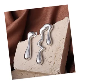 Gros plan de boucles d'oreilles argentées asymétriques au design de lave fluide sur pierre