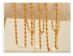 Détail de colliers dorés avec perles ovales en métal et pendentifs en perle baroque