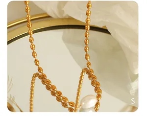 Détail macro d'un pendentif en perle baroque sur un collier de perles dorées brillantes