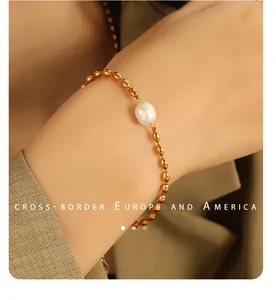 Gros plan d'un bracelet en titane doré orné d'une perle naturelle blanche de forme ovale