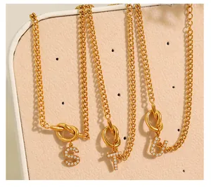 Detail van gouden knoopkettingen met zirkonia-ingelegde S, T, U letterhangers voor dames