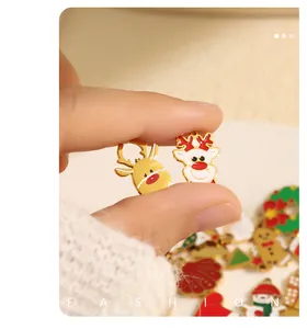 Detailansicht von Mini-Emaille-Weihnachtshängern mit Rentier und Schneemann auf Fingerkuppen