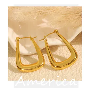 Detailed close-up of gold-plated U-shaped geometric earrings in a shell prop