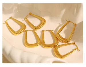 Close-up of three pairs of 18k gold plated U-shaped chunky hoops in a white ceramic dish