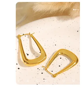 Modern U-shaped 18k gold plated titanium steel earrings on a decorative ceramic dish