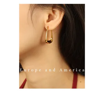 Close-up of gold hollow U-shaped geometric earrings with high-polished mirror finish