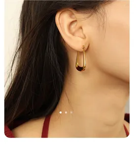 Close-up of polished 18k gold plated U-shaped hoop earrings on a female model