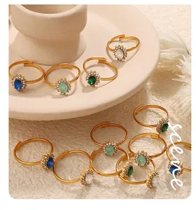 Dettaglio di anelli d'oro regolabili con pietre ovali colorate con montatura a halo