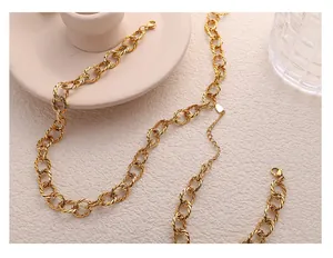 Detail of gold twisted curb chain necklace featuring textured rings and lobster clasp