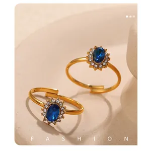 Dettaglio anello dorato regolabile con zircone blu a girasole e cristalli scintillanti