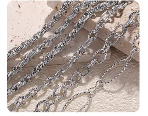 Close-up of various silver Cuban and cable chain textures on a natural stone surface