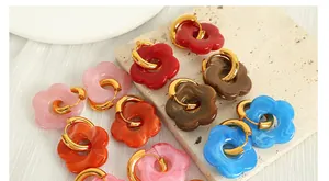 Detailed macro view of vibrant resin camellia flower charms on gold-plated hoop earrings
