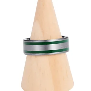 Close-up of brushed tungsten ring with two green resin inlays on a wooden display stand