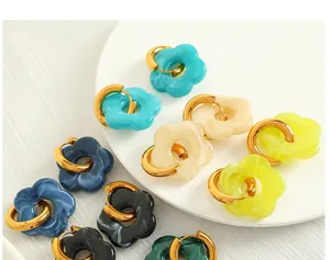 Macro shot of colorful resin flower earrings with gold metal hoops in various pastel colors