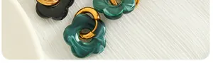 Macro shot of gold camellia earrings featuring marbled green and black resin flower pendants