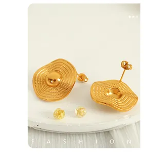 Macro shot of gold textured earrings with fine concentric wave patterns and butterfly backs
