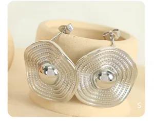 Macro detail of silver square earrings with wavy edges and concentric textured pattern