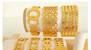 Detailed close-up of 18K gold-plated textured bangles on a white display stand