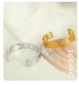 Detail view of gold and silver textured hollow link bangles on a silk background