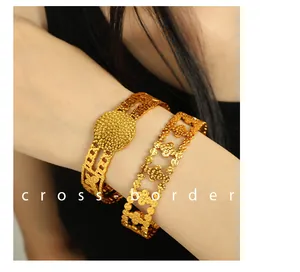 Detail of 18K gold plated bangle set with hammered texture and clover cut-out design