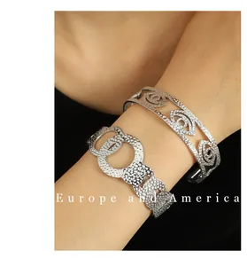 Detail of 18K gold plated textured open bangles with clover and cutout motifs