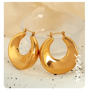 Close-up of chunky gold hoop earrings with polished finish on a ceramic tray