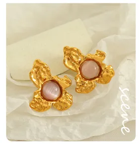 Detail of vintage gold flower earrings with pink cat-eye stone and hammered texture