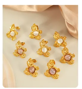 Detailed view of vintage gold flower earrings with opal beads on beige background
