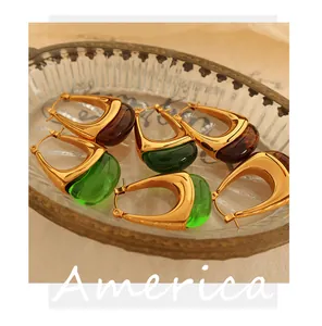 Close-up of vintage U-shaped resin hoop earrings in amber and green with gold plating