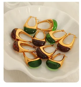 Macro detail of amber resin teardrop earrings in gold U-shaped setting on shell tray