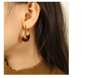 Close-up of teardrop amber resin hoop earrings with elegant golden metallic finish