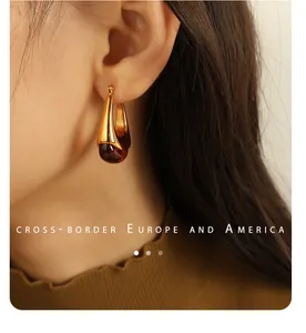 Close-up of golden teardrop earrings with amber resin stones on model's ear