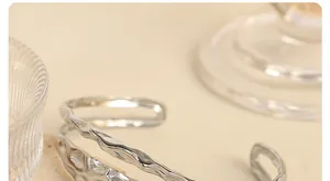 Macro detail showing silver irregular hollowed bangle with molten texture and metallic finish