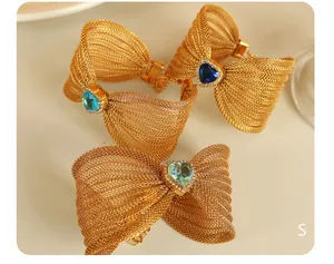 Detalle de pulsera de lazo en malla dorada con gema de corazón y cristales finos