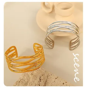 Macro view of gold and silver hollow wavy cuff bracelets with elegant layered design