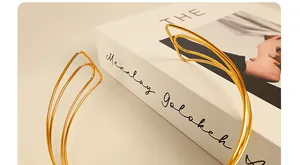 Detail of a minimalist gold triple-layered metal collar necklace with wave-shaped ends