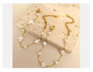 Détail de parure bijoux coquillage dorée avec trèfle et croix sur pierre naturelle