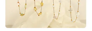 Détail de colliers dorés avec étoiles en coquillage, fleur et croix suspendues