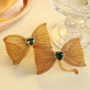 Gouden vlinderarmband met groene hartsteen en zirkonia-accenten op satijnen achtergrond