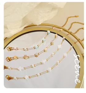 Détail de quatre pendentifs coquillage dorés en étoile, croix et trèfle sur miroir