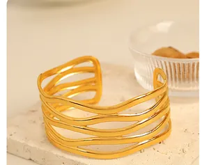 Detail shot of 18K gold-plated cuff bracelet with intricate hollow wavy design