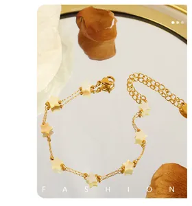 Gros plan d'un bracelet doré avec breloque étoile en nacre et fermoir mousqueton