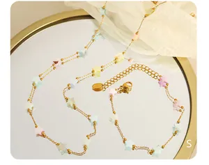 Détail d'un collier doré orné d'étoiles macaron colorées sur une surface miroir